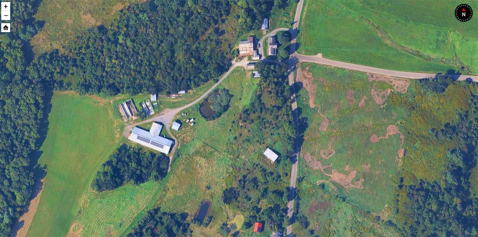An overhead view of a dairy farm surrounded by green fields and forests.